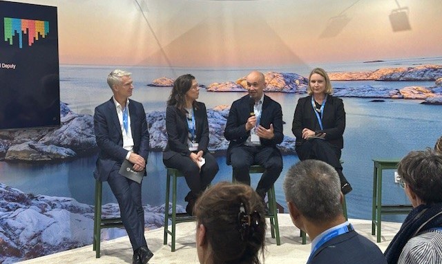 4 people sitting on a stage giving a presentation