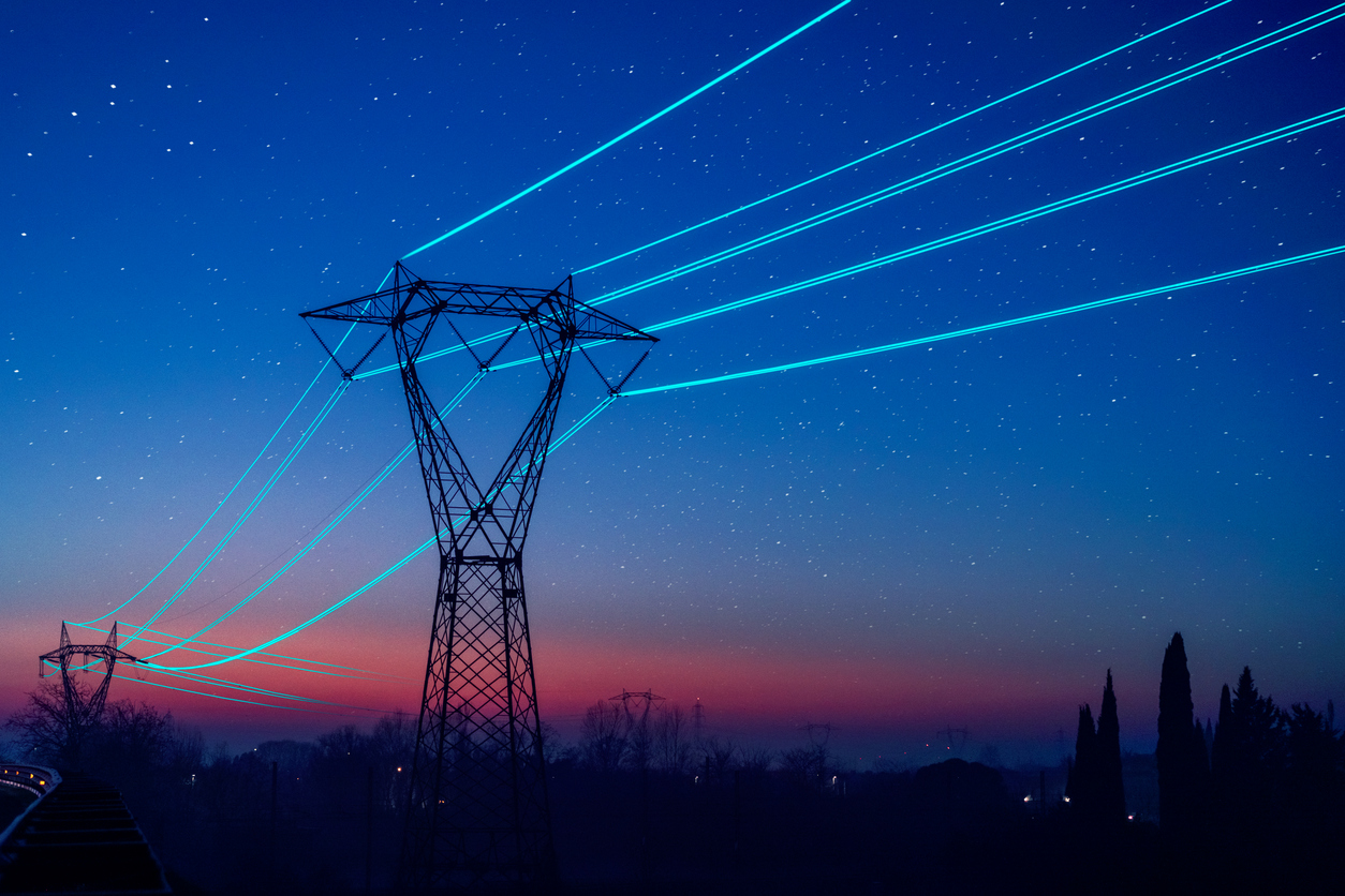 Electricity pilon with glowing cables over sunset sky